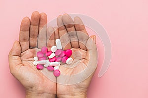 Hand holding medicine pills on pink background for medical and healthcare concept