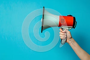 Hand holding megaphone isolated on blue background