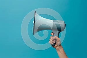 Hand holding megaphone isolated on blue background