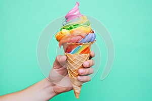 hand holding melted rainbow sherbet in waffle cone