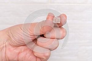 A hand holding micro sim card in fingers, telecommunication technology