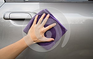 Hand holding microfiber cloth polishing gray car