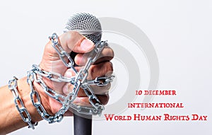 Hand holding microphone and have chain on fist hand with 10 december international world HUMAN RIGHTS DAY text