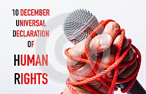 Hand holding microphone and have roped on fist hand with 10 december universal declaration of HUMAN RIGHTS text