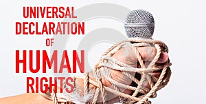 Hand holding microphone and have roped on fist hand with universal declaration of HUMAN RIGHTS text