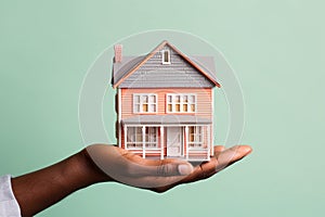 Hand holding a miniature house model. Real estate, investment, property insurance, mortgage, home loan, and savings concept.