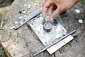 Hand holding minted roman coin on a minting device