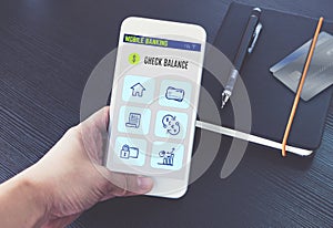 Hand holding mobile banking app on screen with black notebook and credit card on black wooden desk,Digital banking technology