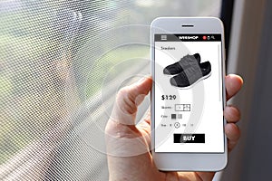 Hand holding mobile ecommerce website with black sneakers page i