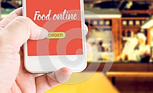 Hand holding mobile with Order food online with blur restaurant