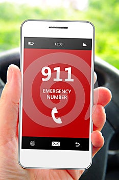 Hand holding mobile phone 911 emergency number in car