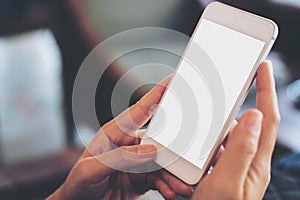 Hand holding mobile phone with blank white screen in vintage cafe