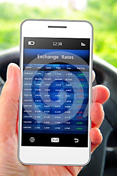 Hand holding mobile phone with exchange rates screen