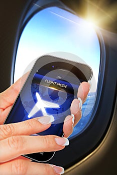 Hand holding mobile phone with flight mode in the airplane