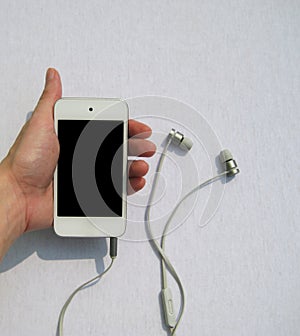 Hand holding mobile phone with headphones