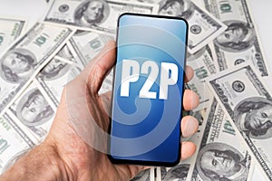 Hand Holding Mobile Phone With P2p Text Against Dollar Bills