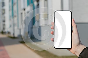 Hand holding mobile phone screen mockup, empty blank smartphone display, blurred building