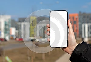 Hand holding mobile phone screen mockup, empty blank smartphone frame, city buildings