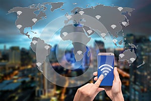 Hand holding mobile phone with wifi icon on world map and city and network connection concept.