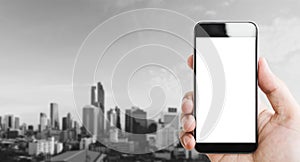 Hand holding mobile smart phone, blank white screen, black and white city background