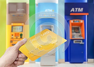 Hand holding mockup gold credit card with colorful cash machine background