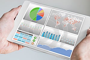 Hand holding modern tablet or mobile device with analytics dashboard