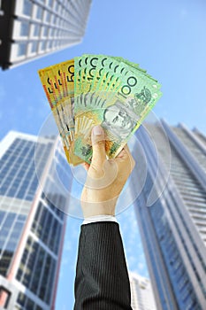 Hand holding money - Australian dollars - with building background