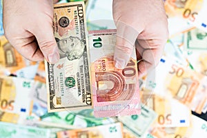 Hand holding money isolated on banknotes background. EURO and USD currency banknotes compared close up. Inflation, finance and