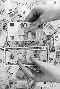 Hand holding money isolated on banknotes background. EURO and USD currency banknotes compared close up. Inflation, finance and