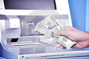 Hand holding money United States dollar (USD) banknotes in front of ATM