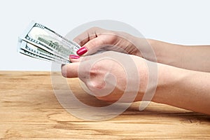 Hand holding money on a wooden table
