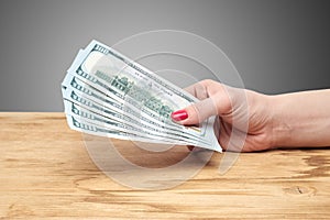 Hand holding money on a wooden table