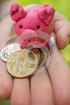 Hand holding moneybox - pink piggy as symbol of savings