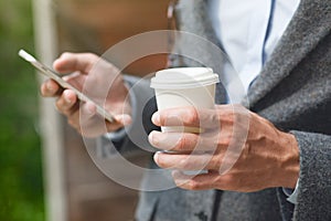 Hand holding morning coffee and reading phone