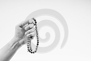 Hand holding a muslim rosary beads or Tasbih on black and white.