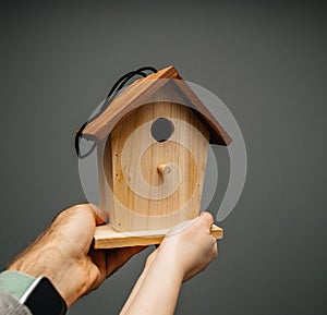 Hand holding new nesting birdhouse gray background