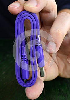 Hand holding new usb 3 purple cable
