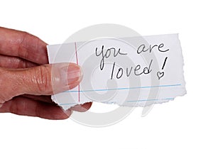 Hand holding note that reads 'You Are Loved'