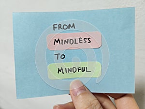 Hand holding a note showing the words From Mindless To Mindful