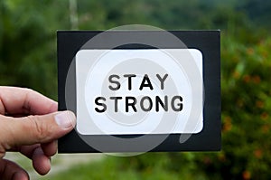 Hand holding notepad with text - Stay strong. Motivational concept