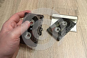 Hand holding an old audio cassette. Tangled tape. Retro medium for recording and playing music.