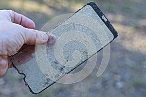 hand holding old dirty broken protective glass of smartphone with cracks