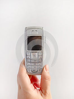 A hand holding old mobile phone on white background, wireless digital technology, communication device