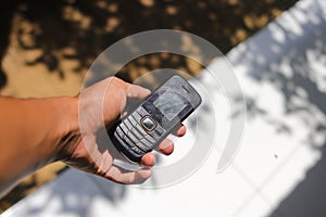 Hand holding an old used cell phone with conventional keypad that were popular in the late 90s and 2000s