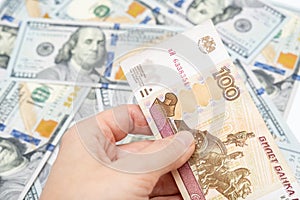 A hand holding one hundred ruble and american dollar banknotes on background, ruble devaluation and usd-rub exchange rate concept