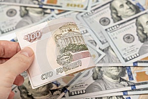 A hand holding one hundred ruble and american dollar banknotes on background, ruble devaluation and usd-rub exchange rate concept