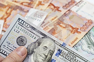 Hand holding one hundred us dollar banknote over russian ruble background