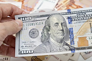 Hand holding one hundred us dollar banknote over russian ruble background, investment concept