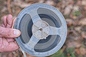hand holding one old plastic black gray magnetic reel