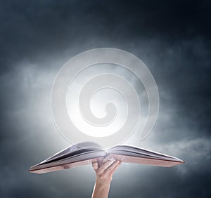 Hand holding on opened magic book